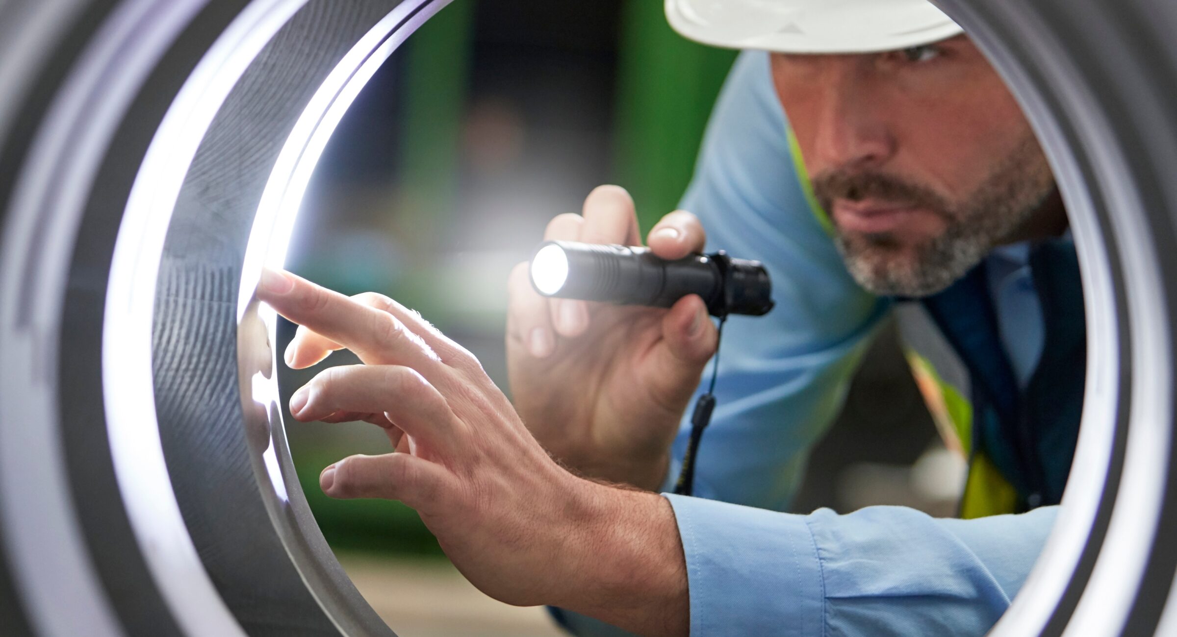 Male engineer with flashlight inspecting steel cylinder